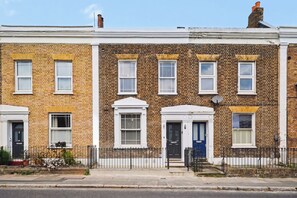 A row of terraced houses with white front doors and windows, a brick facade, and a black metal fence. - Lovely 5BDR Family Home Near Greenwich Park (Greater London)