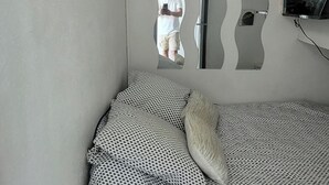 Ein Schlafzimmer mit einem Bett, einem Spiegel und einem an der Wand montierten Fernseher.