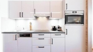 Uma cozinha moderna com armários brancos, uma lava-louças e um forno.