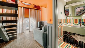 A hotel room with a herringbone patterned floor, a sofa, a television, and a bathroom with a colorful mosaic backsplash. - Axis Avenida (Viana do Castelo)