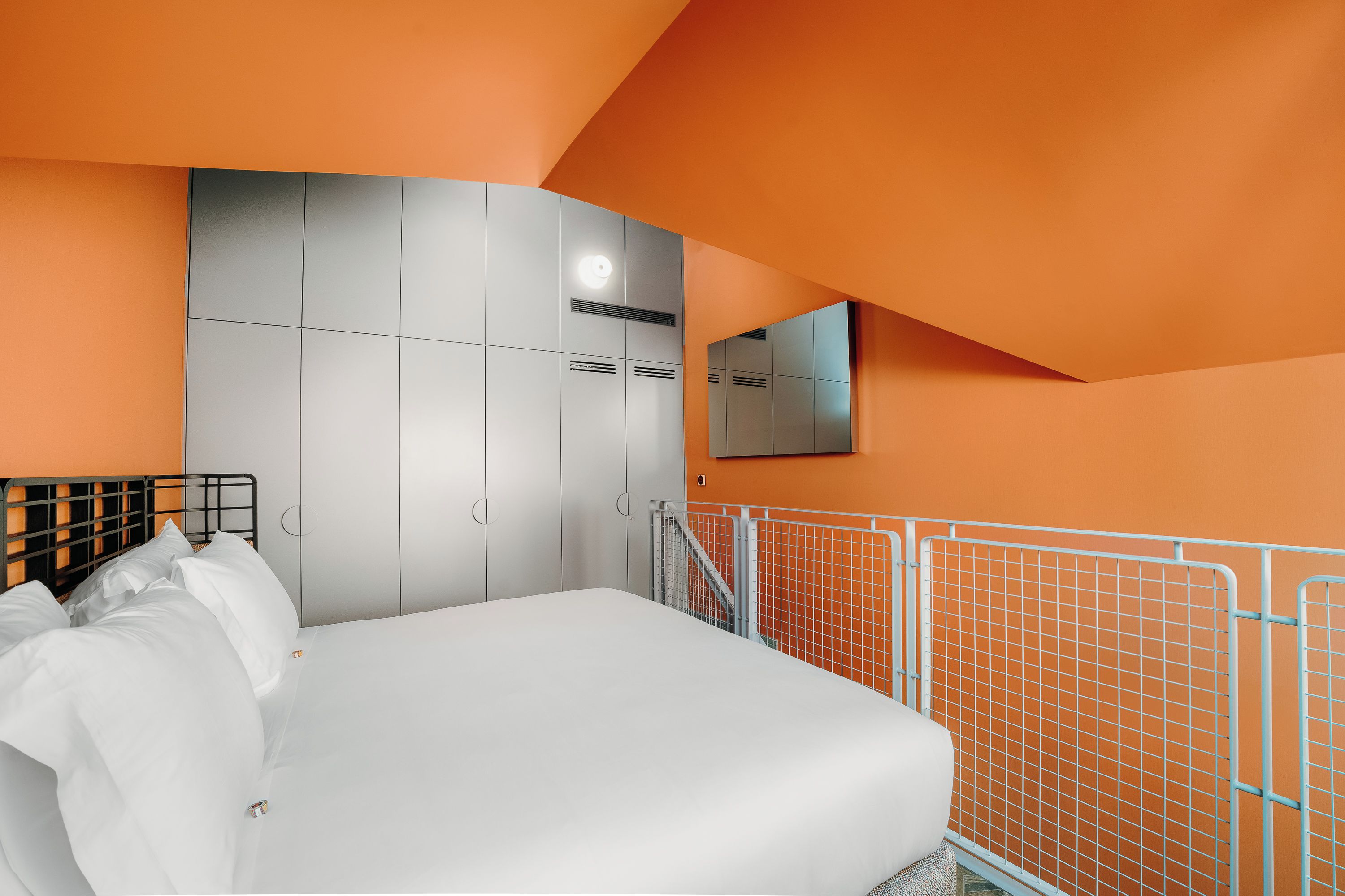 Une chambre à coucher avec un lit, une armoire, un miroir et une rambarde.