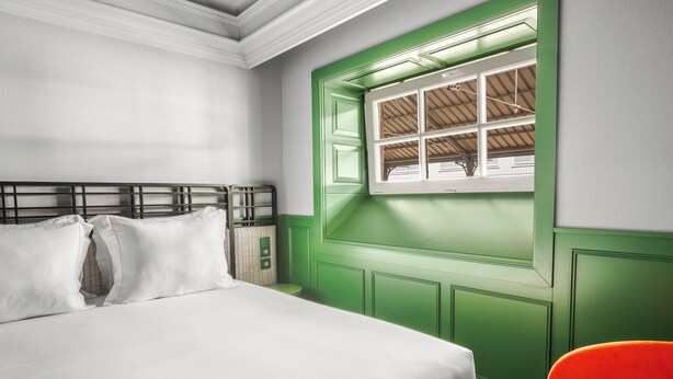 A bedroom with a bed, a green window, and a red chair. - Axis Avenida (Viana do Castelo)