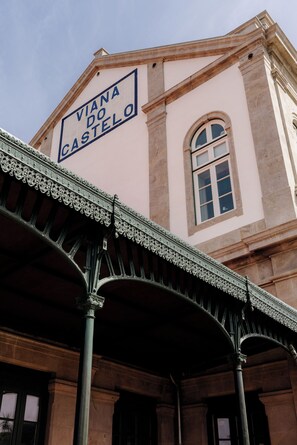 A building with a sign reading 'Viana do Castelo' and a covered entrance with ornate metalwork.