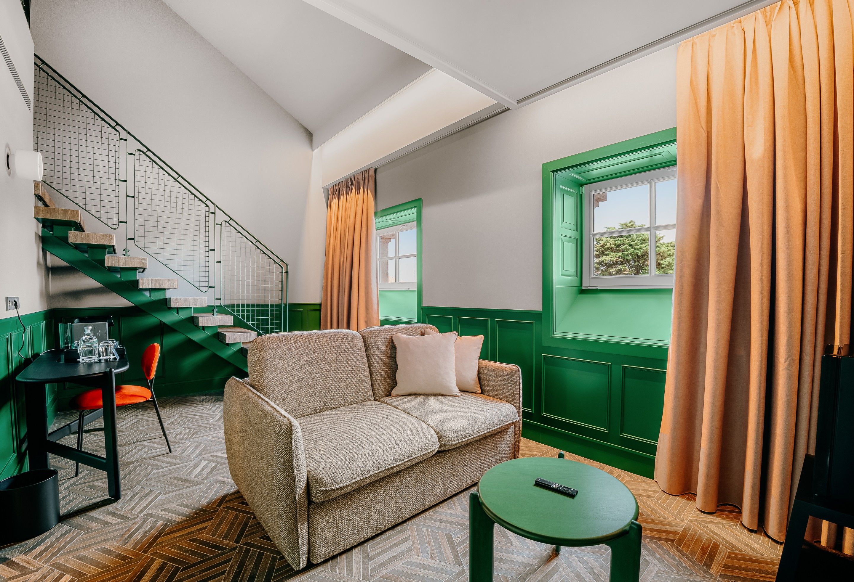 A room with a green and white color scheme, a sofa, a small table, and a window with curtains.