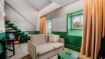 A room with a green and white color scheme, a sofa, a small table, and a window with curtains.