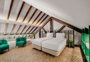 A bedroom with a sloped ceiling, a bed with white bedding, a green chair, and a small table. - Axis Avenida (Viana do Castelo)