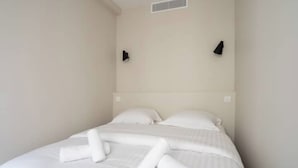 Une chambre d’hôtel avec un lit, des oreillers et des serviettes soigneusement pliées.