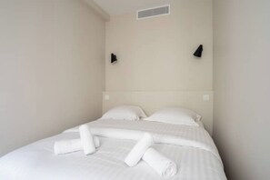 Ein Hotelzimmer mit einem Bett, Kissen und ordentlich gefalteten Handtüchern.