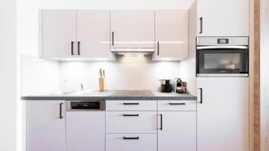 Une cuisine moderne avec des meubles blancs, un lave-vaisselle et un four.