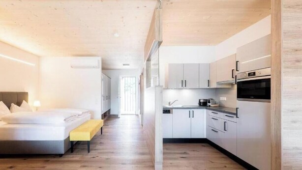 Une chambre d’hôtel moderne équipée d’un lit, d’une table de chevet et offrant une vue sur la cuisine.