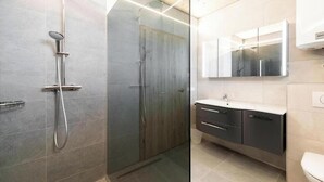 Une salle de bain moderne avec une douche à parois de verre, un meuble-lavabo avec un miroir et des toilettes.