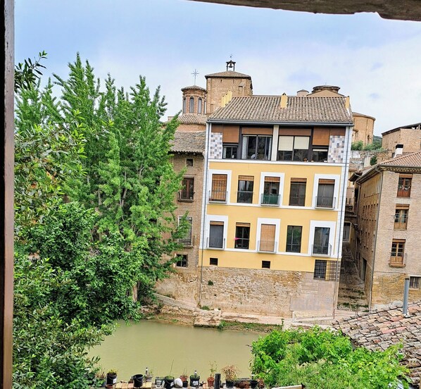 A multi-story building with a yellow facade, a stone base, and a small courtyard with a pond.