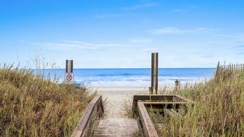 A wooden pathway leading to a beach with a no swimming sign.