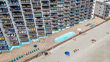 A high-rise hotel with multiple balconies, a swimming pool, and beach access.