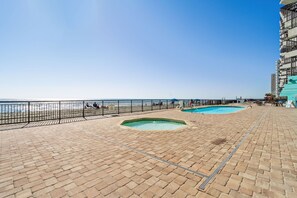 A pool area with two hot tubs and a brick deck. - Royal Garden Resort 1214 (Murrells Inlet)