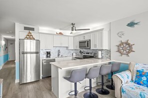 A modern kitchen with a central island, stainless steel appliances, and a ceiling fan. - Royal Garden Resort 1214 (Murrells Inlet)