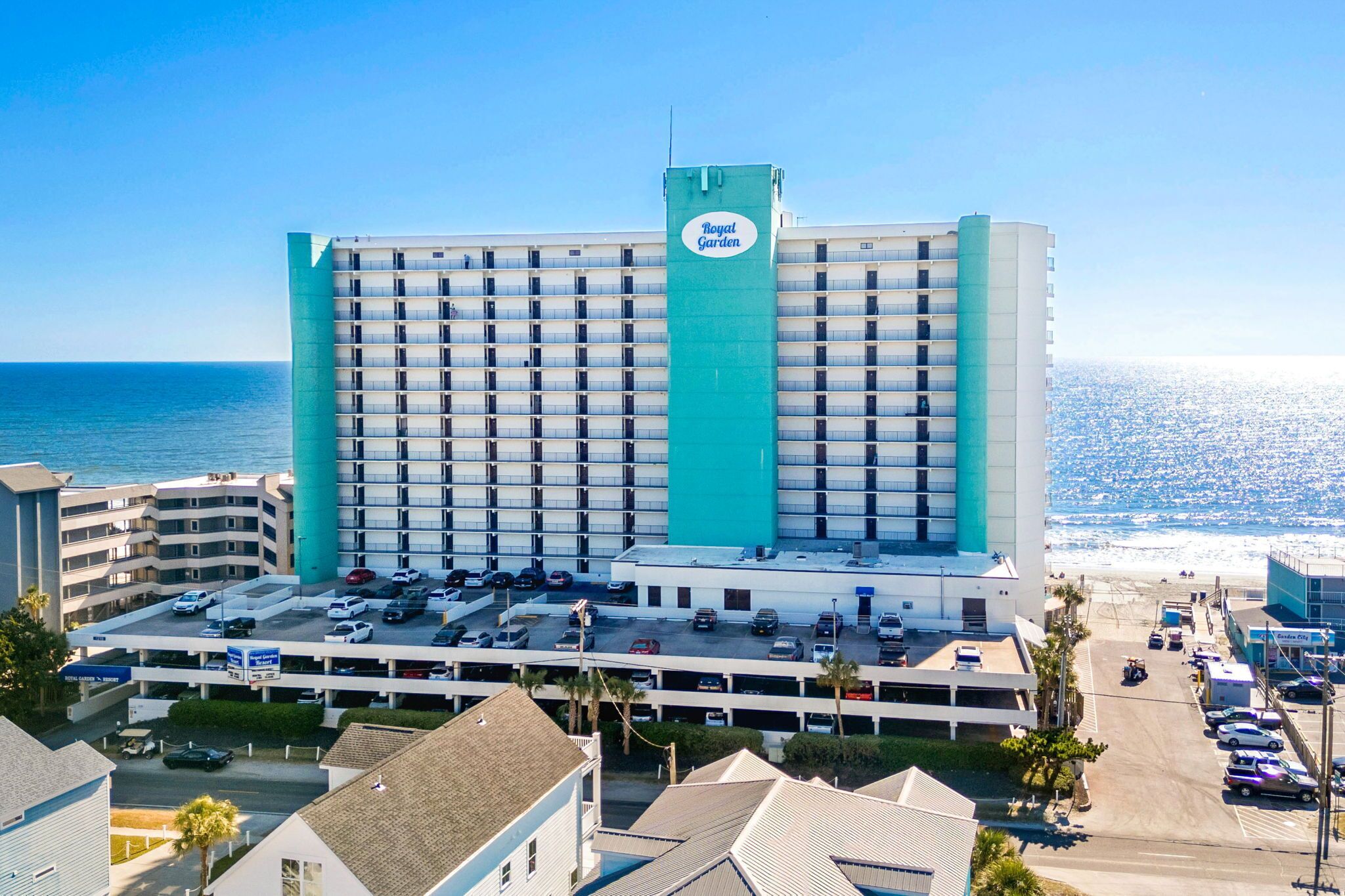 A hotel with multiple floors, a parking lot, and a view of the ocean.