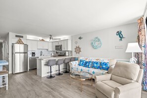 A modern kitchen with a central island, bar stools, and a dining table. - Royal Garden Resort 1214 (Murrells Inlet)