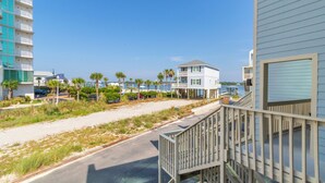 A beachfront property with a wooden deck, a two-story building, and a view of the ocean.