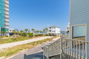 A beachfront property with a wooden deck, a two-story building, and a view of the ocean.