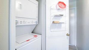 A laundry room with a front-loading washing machine and a drying rack.
