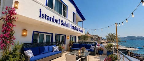Hotel Istanbul Sahil & Beach con posti a sedere all'aperto, vista sul mare e un balcone con luci a stringa.