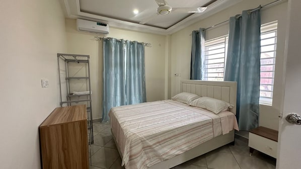 A bedroom with a bed, a wardrobe, a ceiling fan, and a window with curtains.