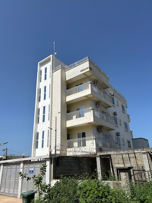 A multi-story building with balconies, air conditioning units, and a gated entrance.