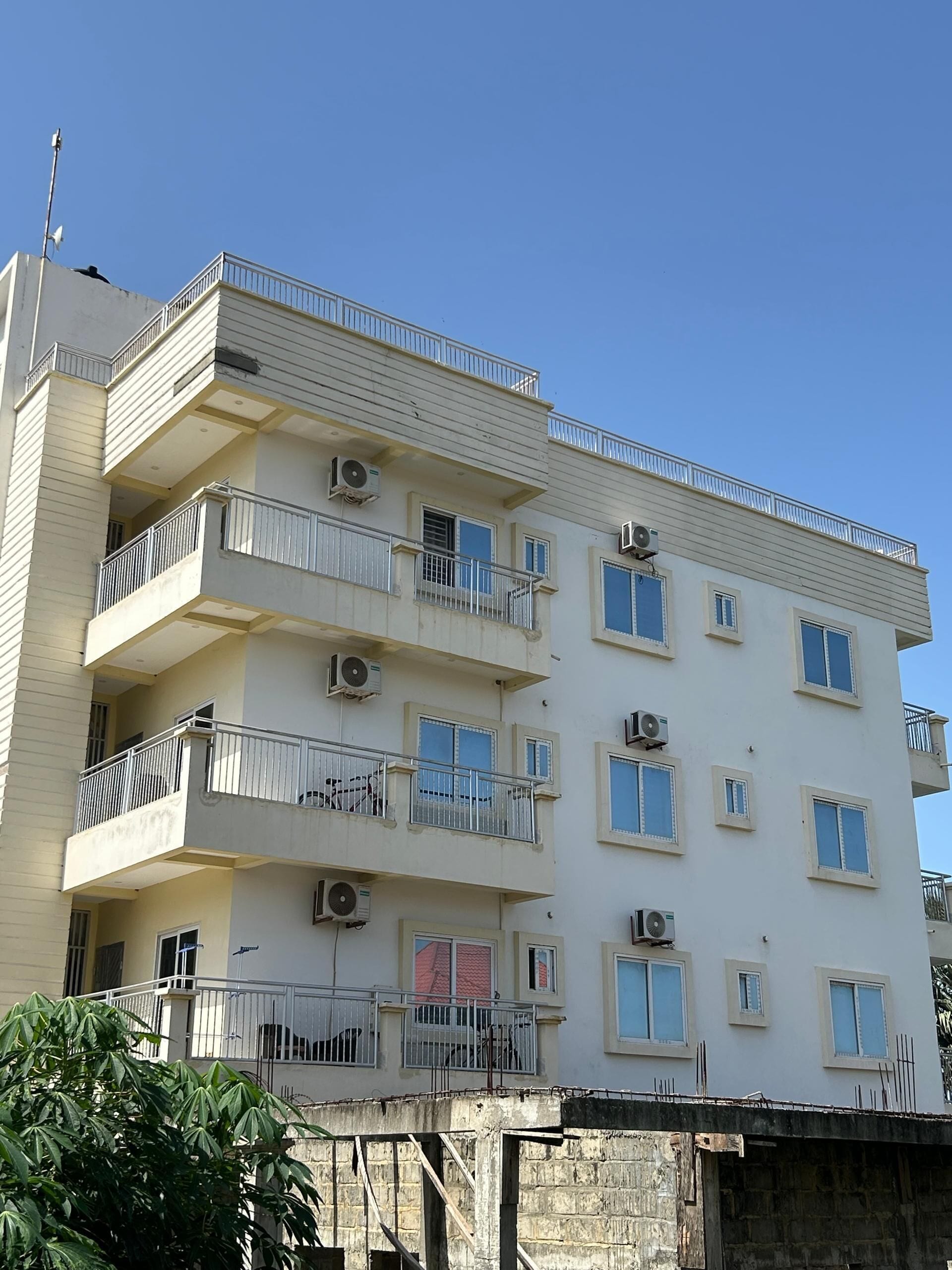 A multi-story building with balconies, air conditioning units, and a clear sky.