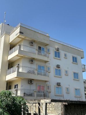 A multi-story building with balconies, air conditioning units, and a clear sky.
