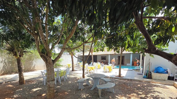 Un'area salotto all'aperto con tavoli e sedie, una piscina e un edificio con ingresso a bordo vasca.