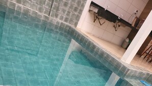 Una piscina con acqua cristallina, bordi piastrellati e uno scarico visibile.