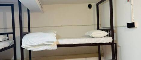 A bunk bed room with three levels, a metal trash can, and a white ceiling with visible wiring.