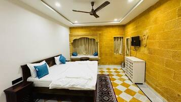 A bedroom with a bed, a ceiling fan, a small white cabinet, and a patterned rug.