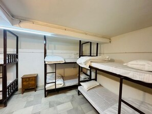 A dormitory room with bunk beds, a small wooden cabinet, and a tiled floor. - Mama Mia Jaisalmer (Jaisalmer)