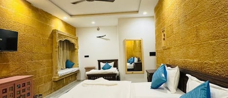 A hotel room with a large bed, a ceiling fan, and a wall-mounted television.