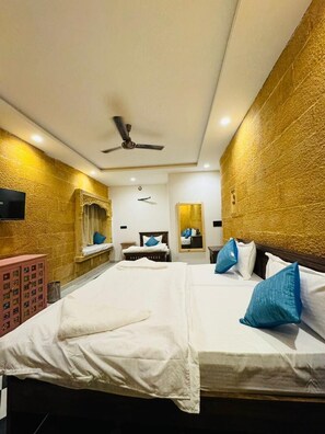 A hotel room with a large bed, a ceiling fan, and a wall-mounted television. - Mama Mia Jaisalmer (Jaisalmer)