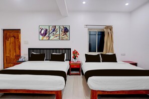 Ein Hotelzimmer mit zwei Betten, einer Holztür, einem mit Vorhängen versehenen Fenster und einem an der Wand hängenden Kunstwerk.