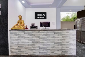 Eine Rezeption mit einer Buddha-Statue, einem Schild, das angibt, dass es sich um ein OYO-Serviced Hotel handelt, und einer Überwachungskamera an der Wand.