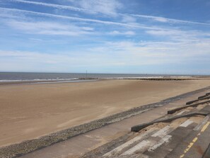 Ein weiter Sandstrand mit einem Felsenmole und blauem Himmel.