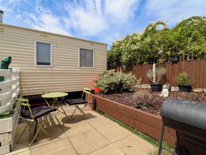 A backyard with a patio area, a grill, and a wooden fence. - Pathway to the sea (Prestatyn)