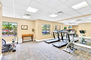 A gym with treadmills, an elliptical, and a bench. - 2 Queen Beds Condo Near Universal Studios With Pool Hot Tub (Orlando)