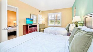 Ein Hotelzimmer mit zwei Betten, einem Fernseher, einem Schreibtisch und einem Stuhl.