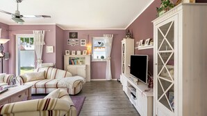 Un salon comprenant un canapé, un téléviseur et un meuble.