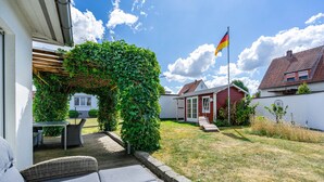 Une propriété résidentielle dotée d’un patio couvert, d’un espace salon extérieur et d’un mât pour drapeau.