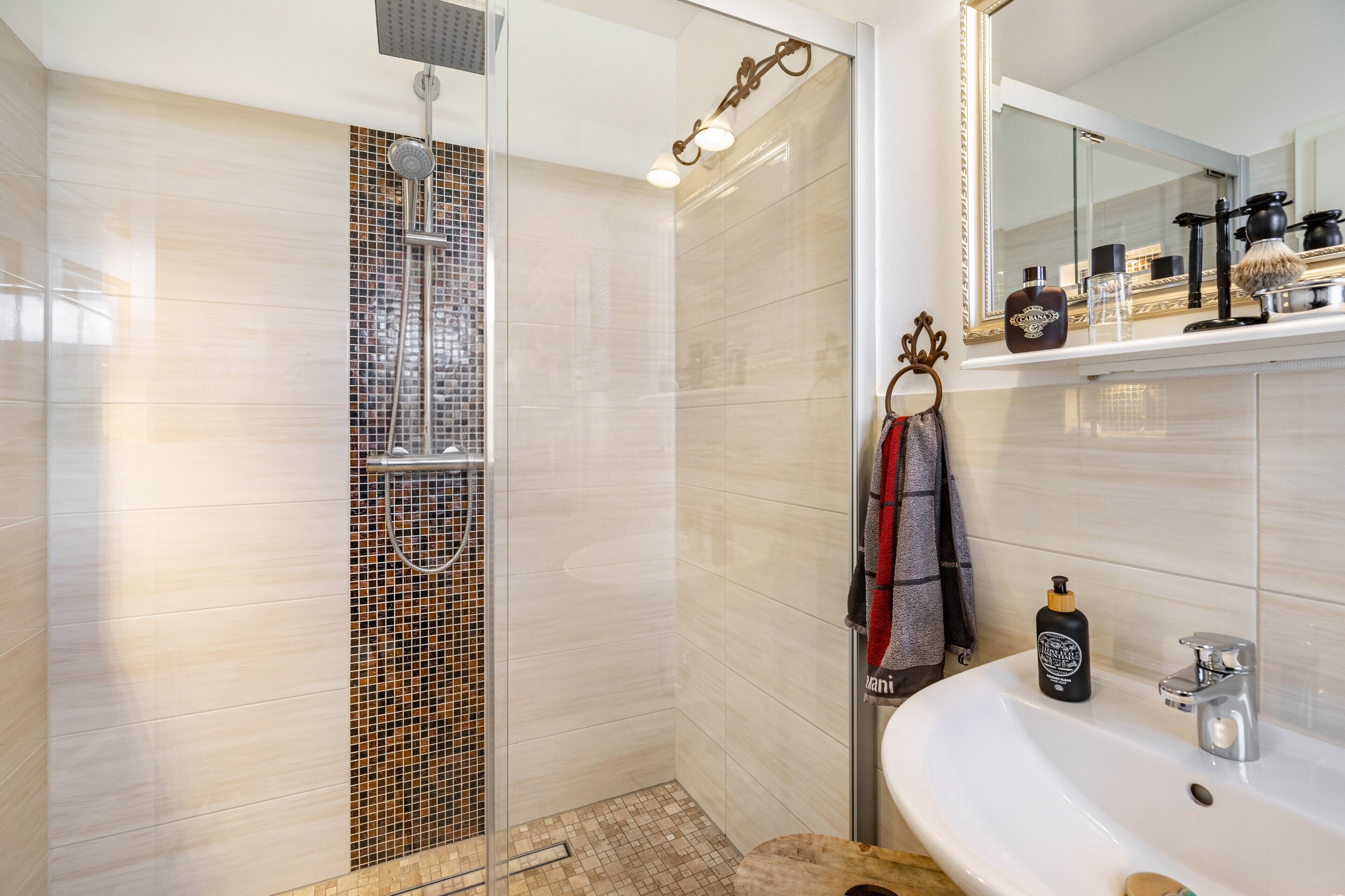 Ein modernes Badezimmer mit Dusche, Waschbecken und Spiegel.