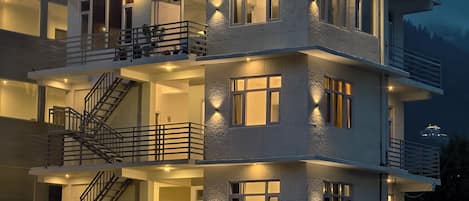 A multi-story building with balconies, staircases, and exterior lighting.