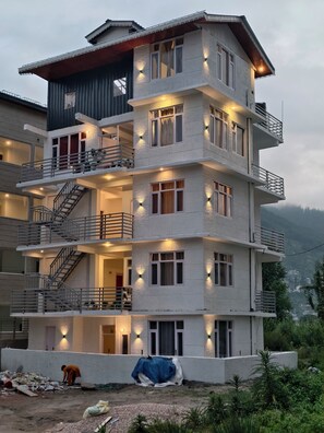 A multi-story building with balconies, staircases, and exterior lighting.