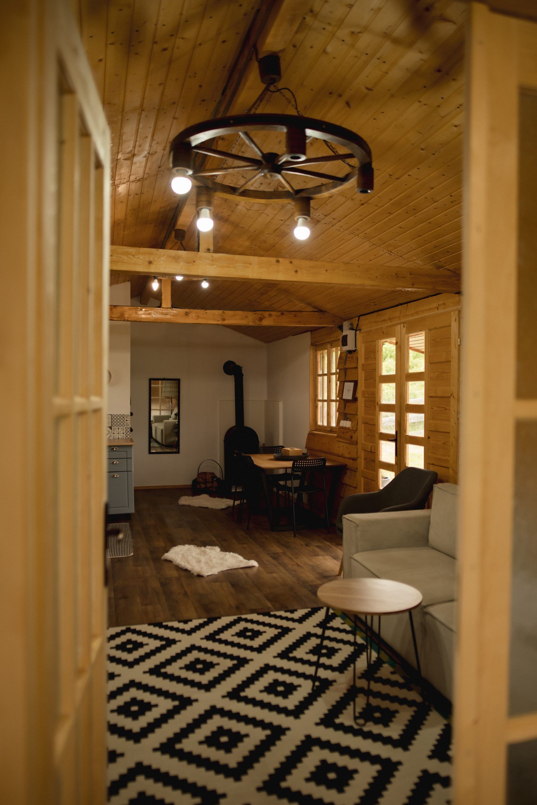 Un interior de madera con comedor, sofá y alfombra estampada.