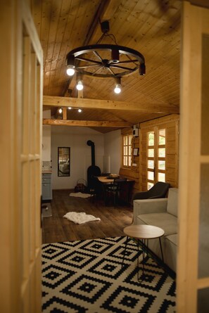 A wooden interior with a dining area, a sofa, and a patterned rug.